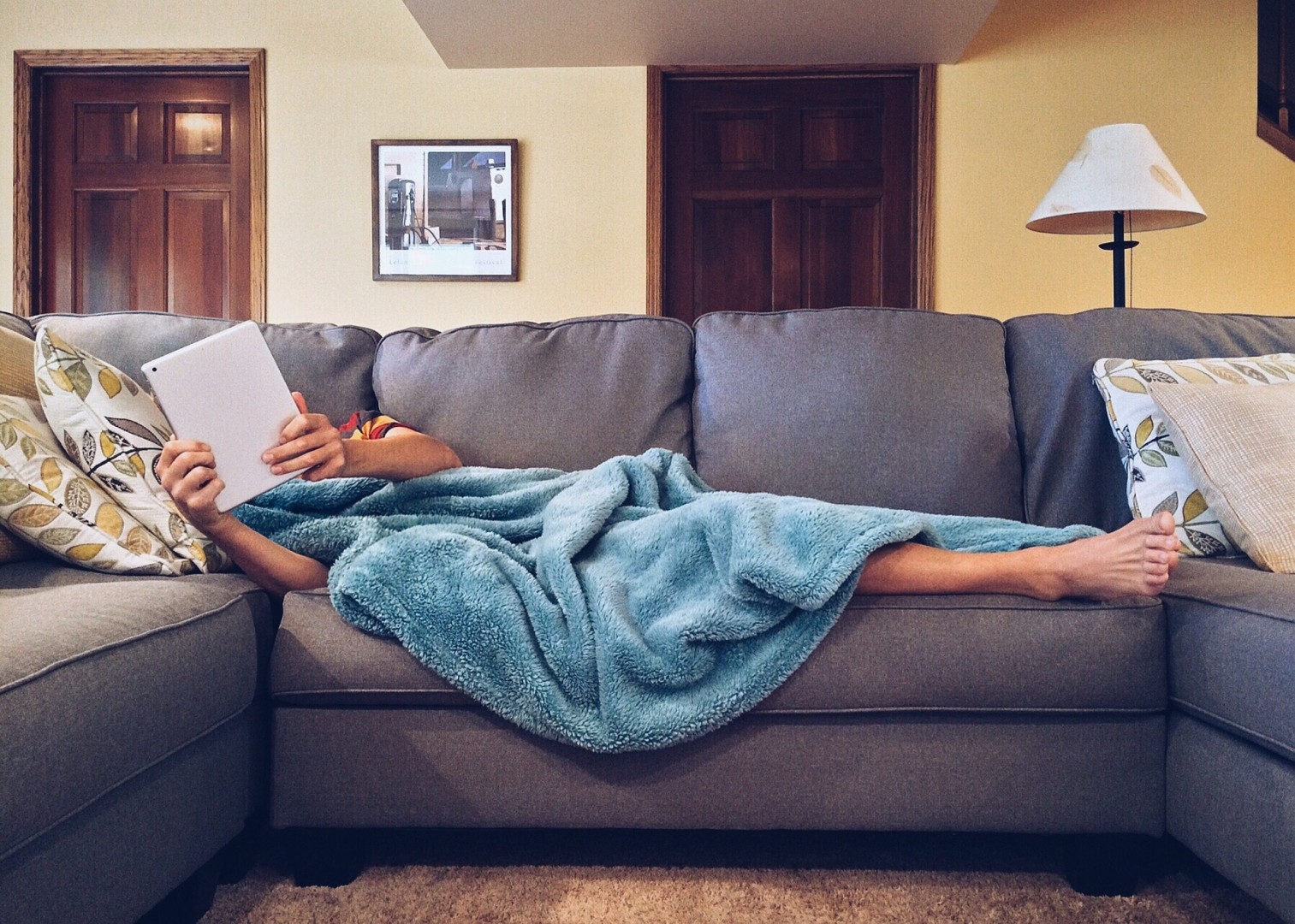 Person lying on a sofa with a tablet