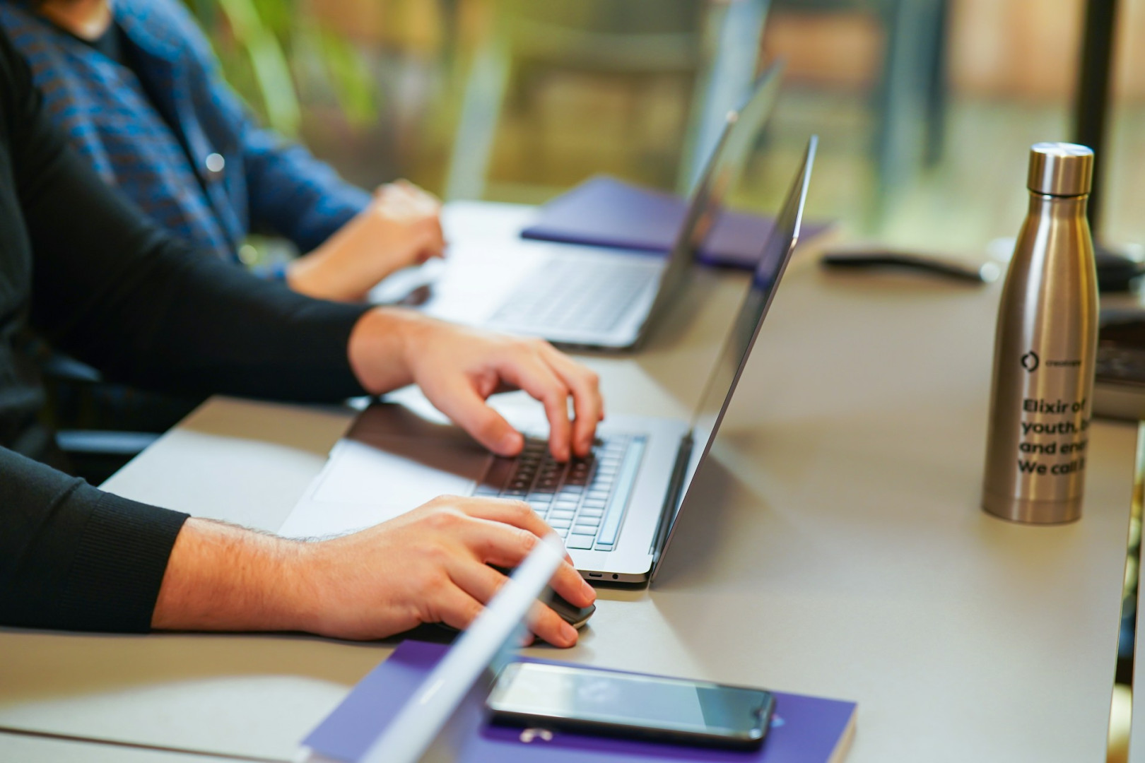 Two people sitting at a table using laptops