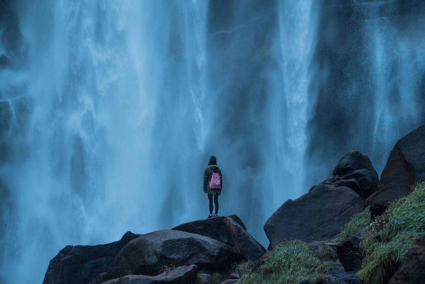 Woman Alone Stood on Rocks Looking At Waterfall